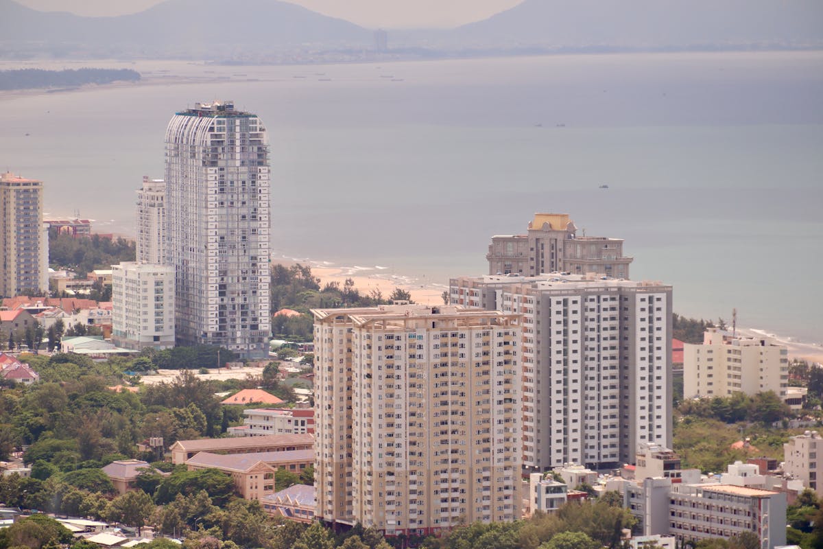 A high-angle view of a coastal city with skyscrapers and ocean in the background.